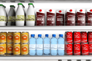 A refrigerated display with milk bottles, chocolate milk cartons, orange soda cans, bottled water, and cola cans. Milk is on the top shelf, while the drinks are organized below in neat rows.